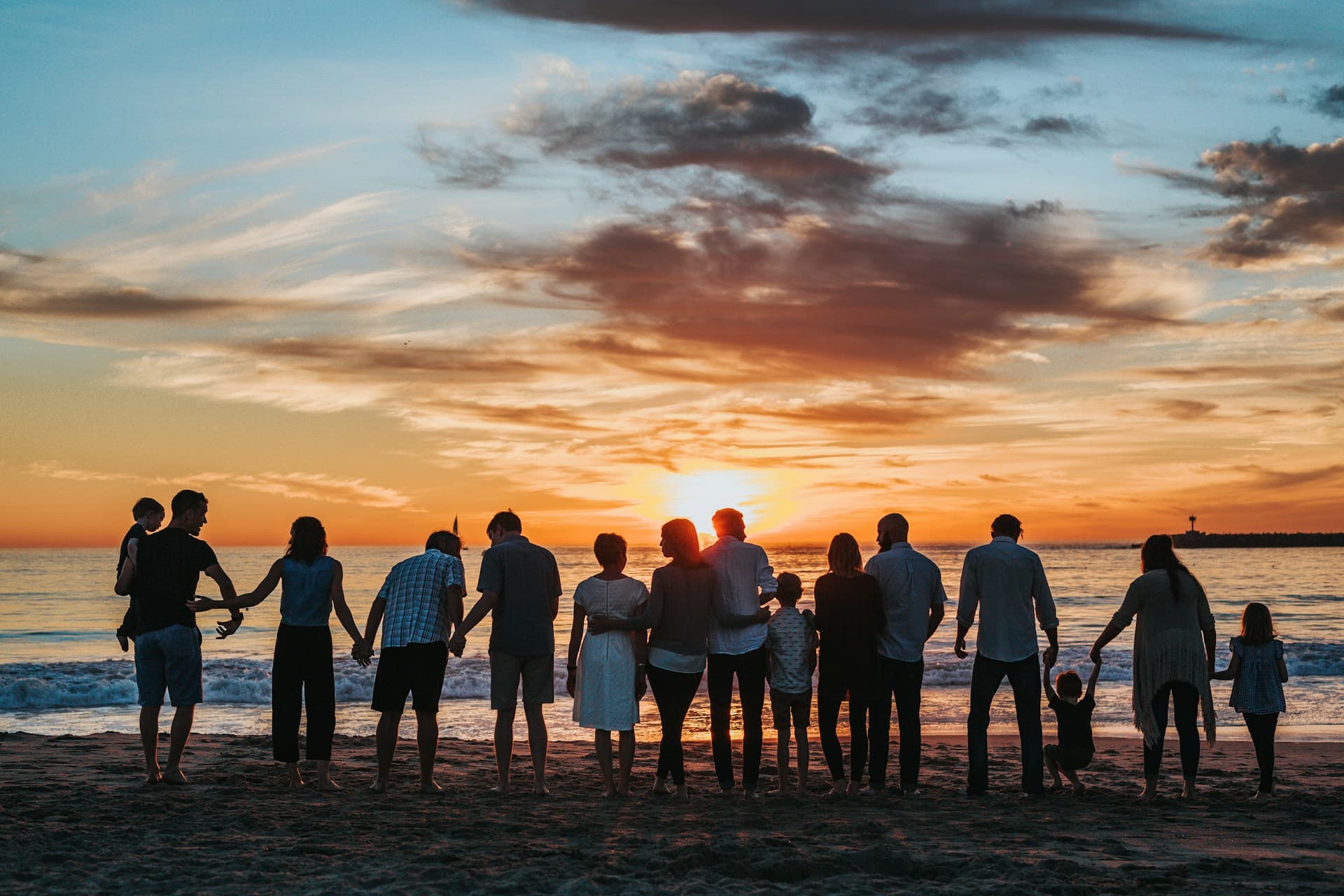 Large family group laughing together on a beach at sunset